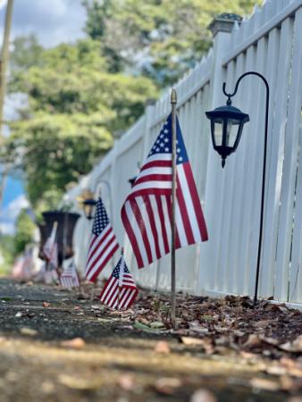 Photo of white picket fence with lanterns and American flags